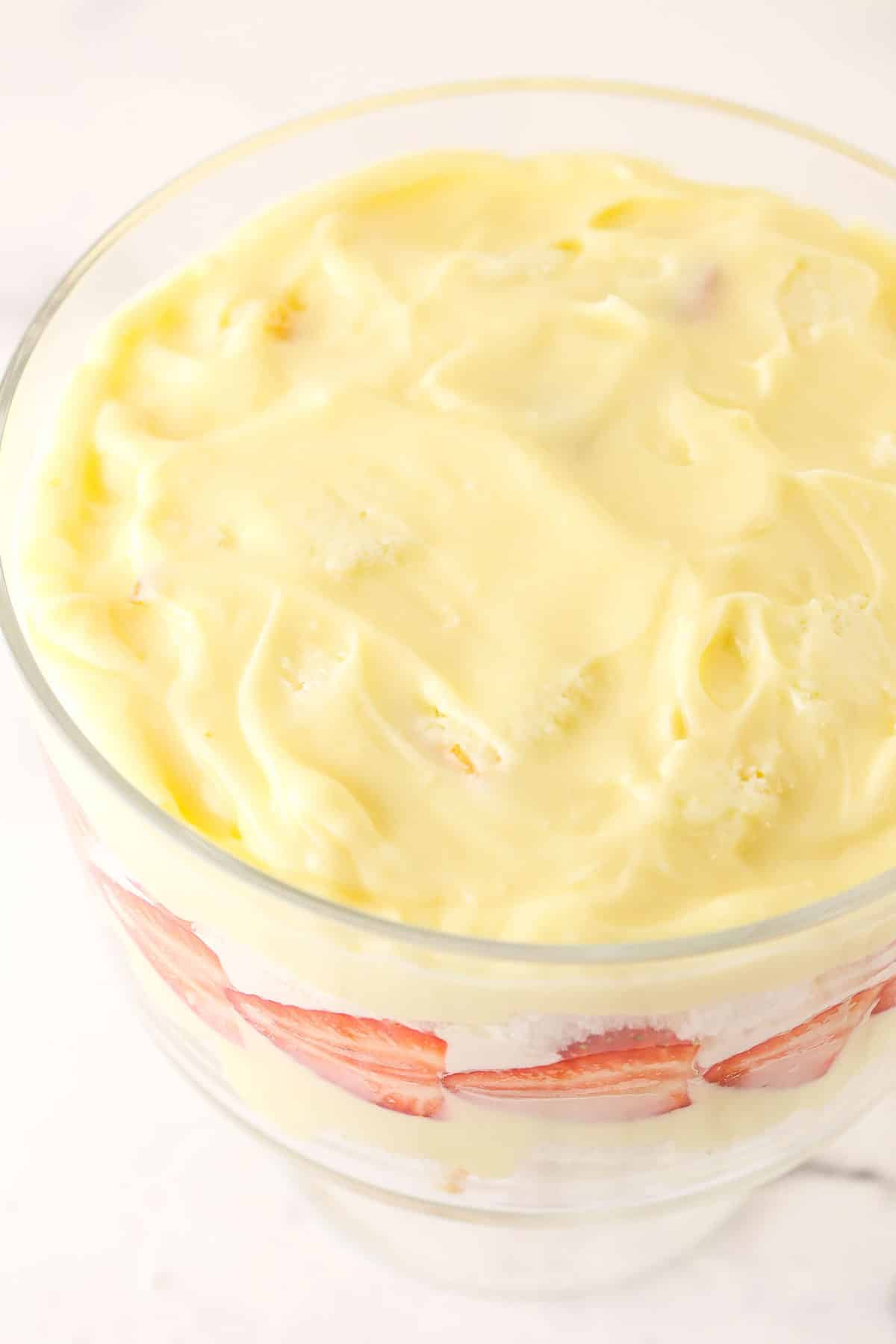 Overhead view of pudding being added on top of the trifle angel food cake layer.