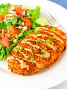 crispy buffalo chicken on white plate with salad