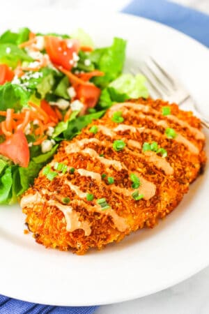 crispy buffalo chicken on white plate with salad