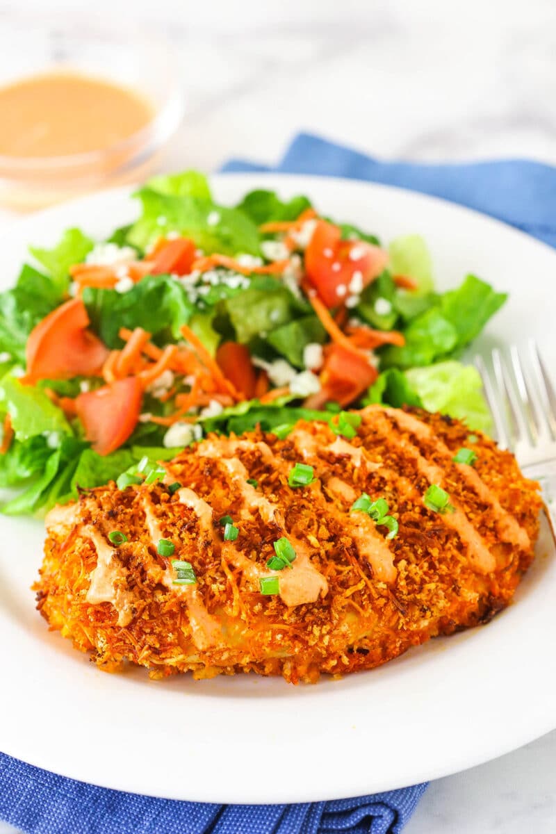 Crispy Buffalo Chicken with salad on white plate and blue napkin