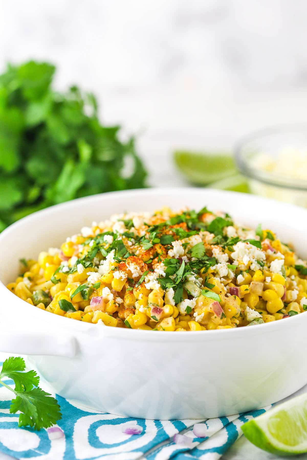 Mexican street corn salad is creamy, zesty, and smoky with just the right amount of spice to complement the sweetness of the corn. Um, yum! Mexican street corn salad in a bowl with cilantro in the background.
