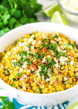 mexican street corn salad in a white bowl on a teal and white napkin