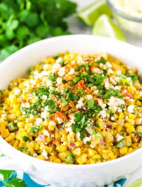 mexican street corn salad in a white bowl on a teal and white napkin