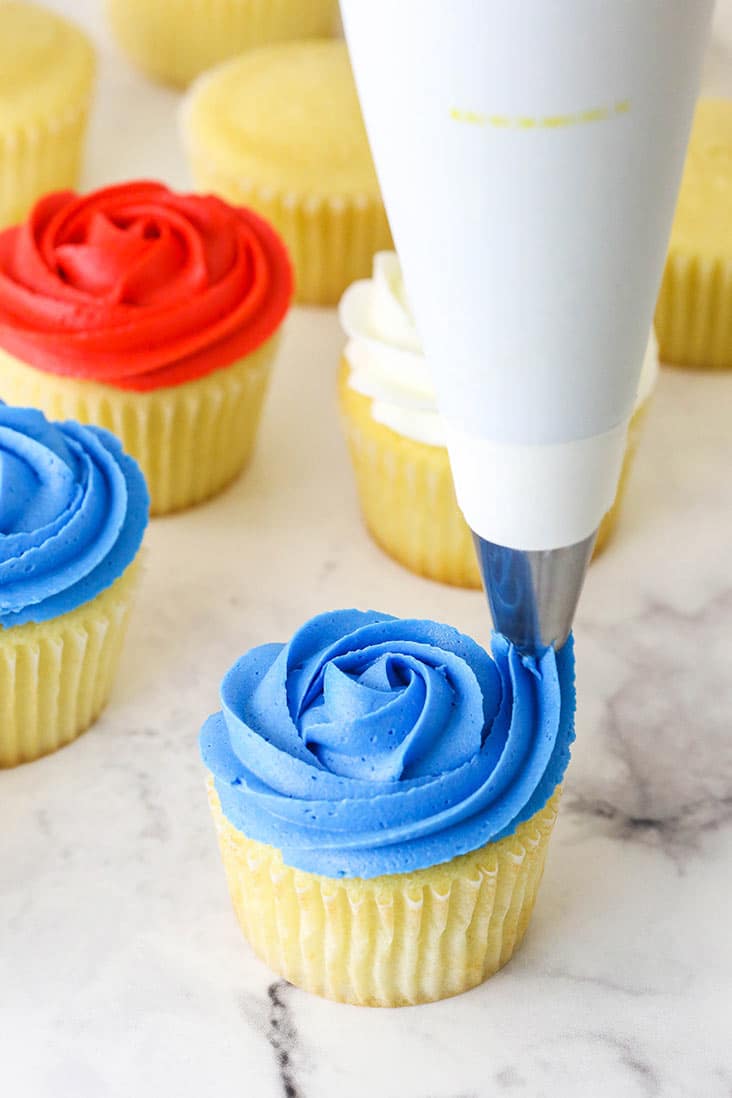 piping blue frosting onto a cupcake
