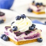 A cheesecake square with blueberries and whipped cream