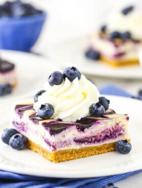 A cheesecake square with blueberries and whipped cream