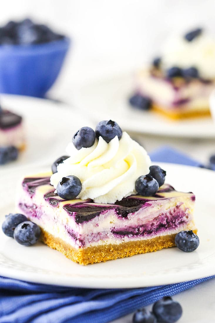 A cheesecake square with blueberries and whipped cream