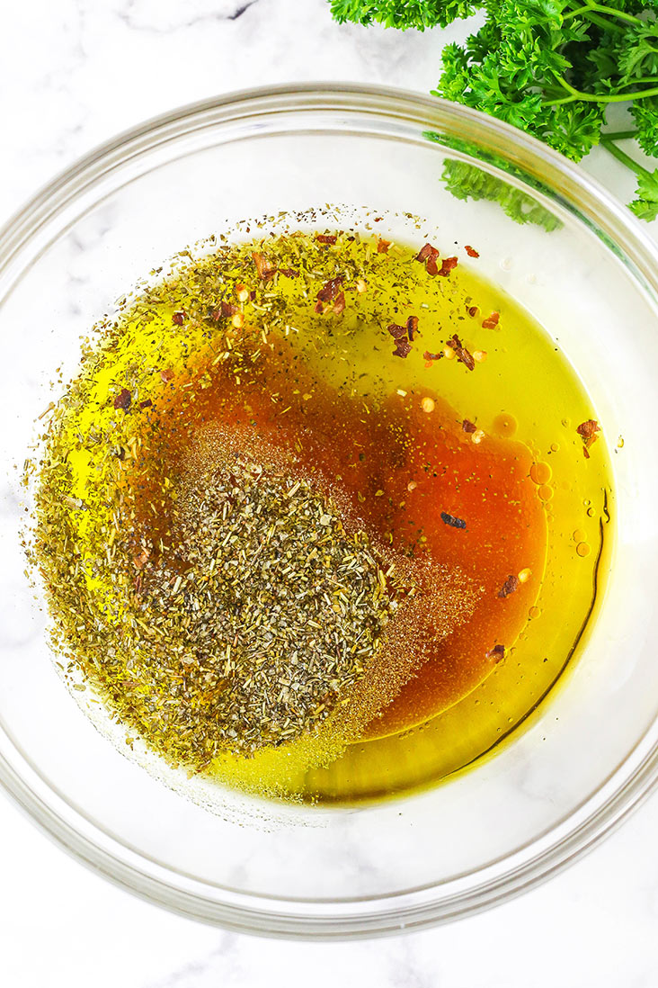 All of the ingredients for homemade Italian dressing in a glass bowl