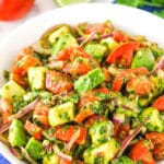 A white bowl of tomato avocado salad