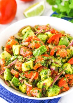 A white bowl of tomato avocado salad