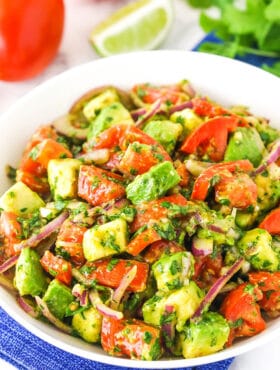 A white bowl of tomato avocado salad