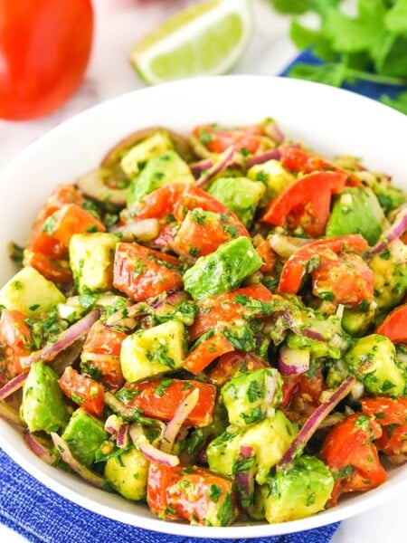 A white bowl of tomato avocado salad