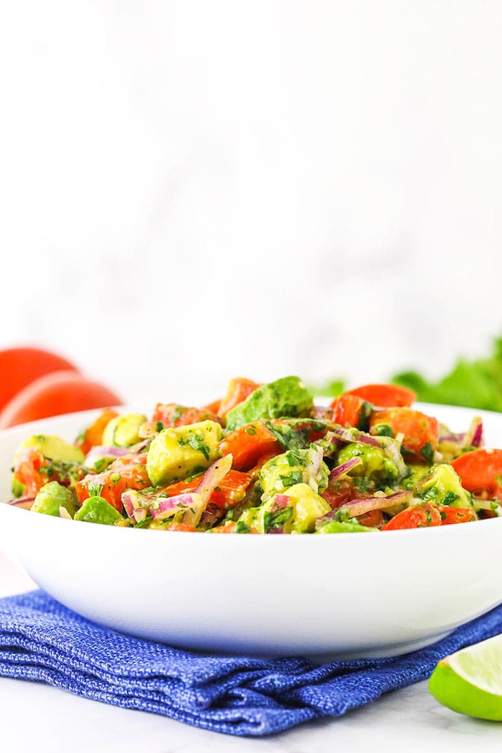 A white bowl of tomato avocado salad