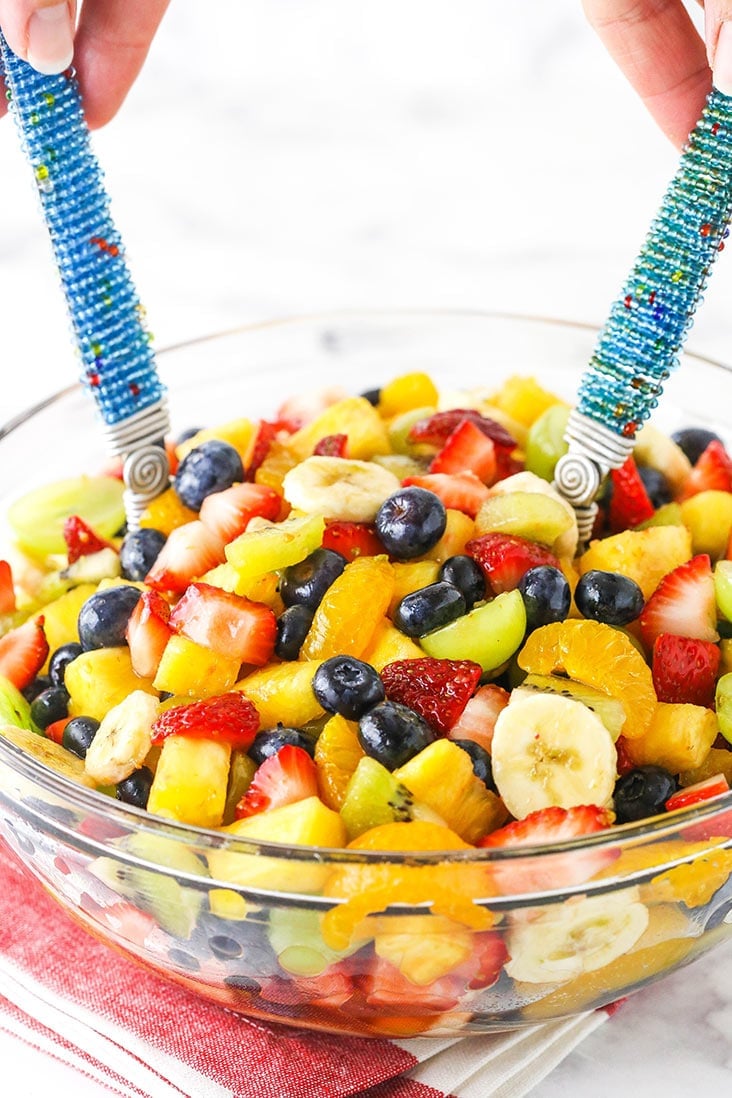 fruit salad in a clear bowl being tossed