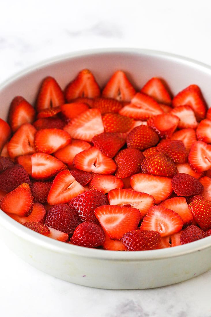 Sliced strawberries lining a round cake pan