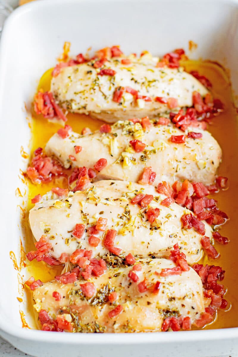 cooked herb chicken and bacon in white casserole dish