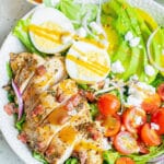 herb chicken cobb salad with dressing in white bowl