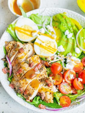 herb chicken cobb salad with dressing in white bowl
