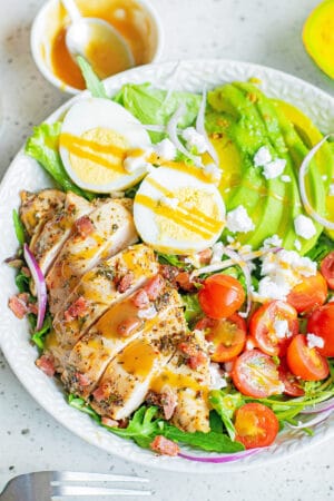 herb chicken cobb salad with dressing in white bowl
