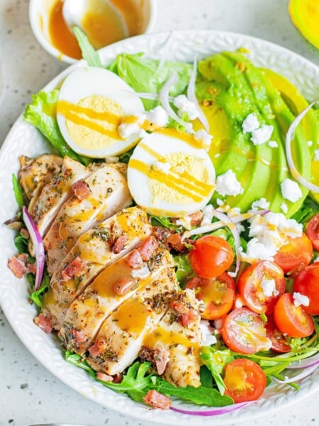 herb chicken cobb salad with dressing in white bowl