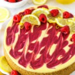 A slice of lemon raspberry swirl cheesecake topped with raspberries and lemon