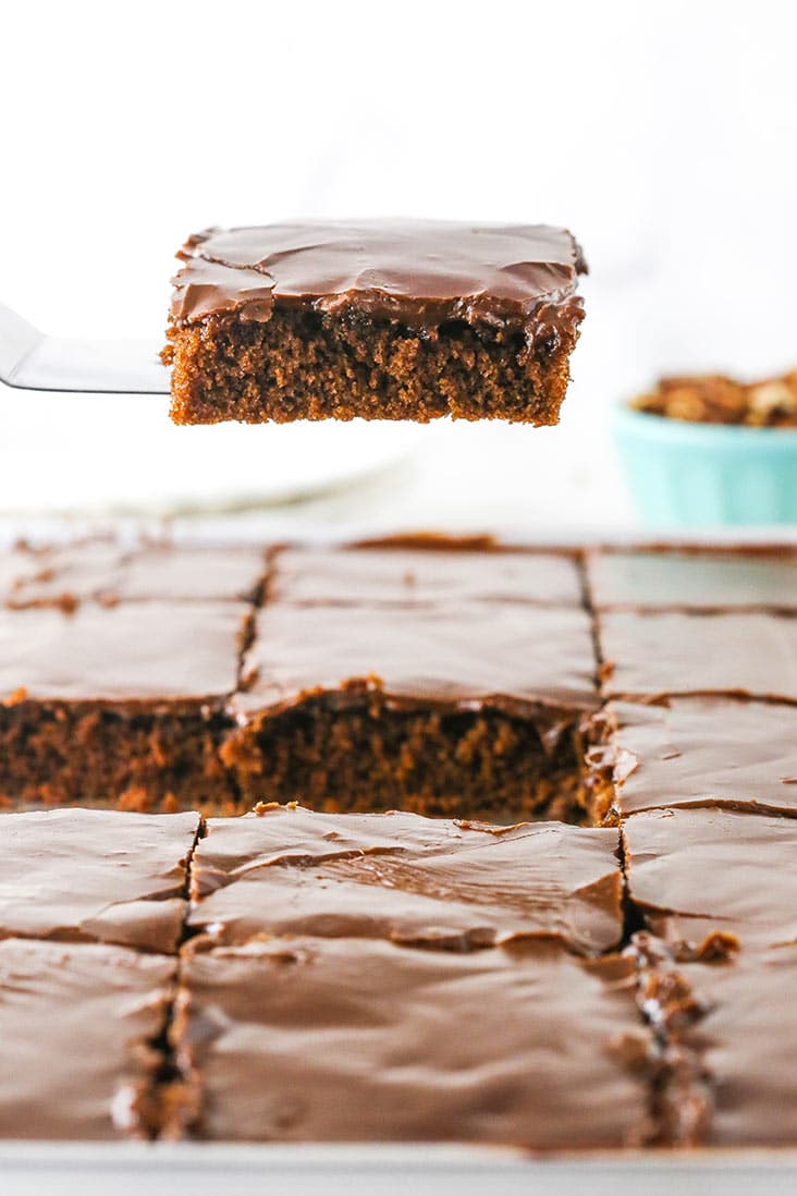 A slice of chocolate cake being served from a sheet pan