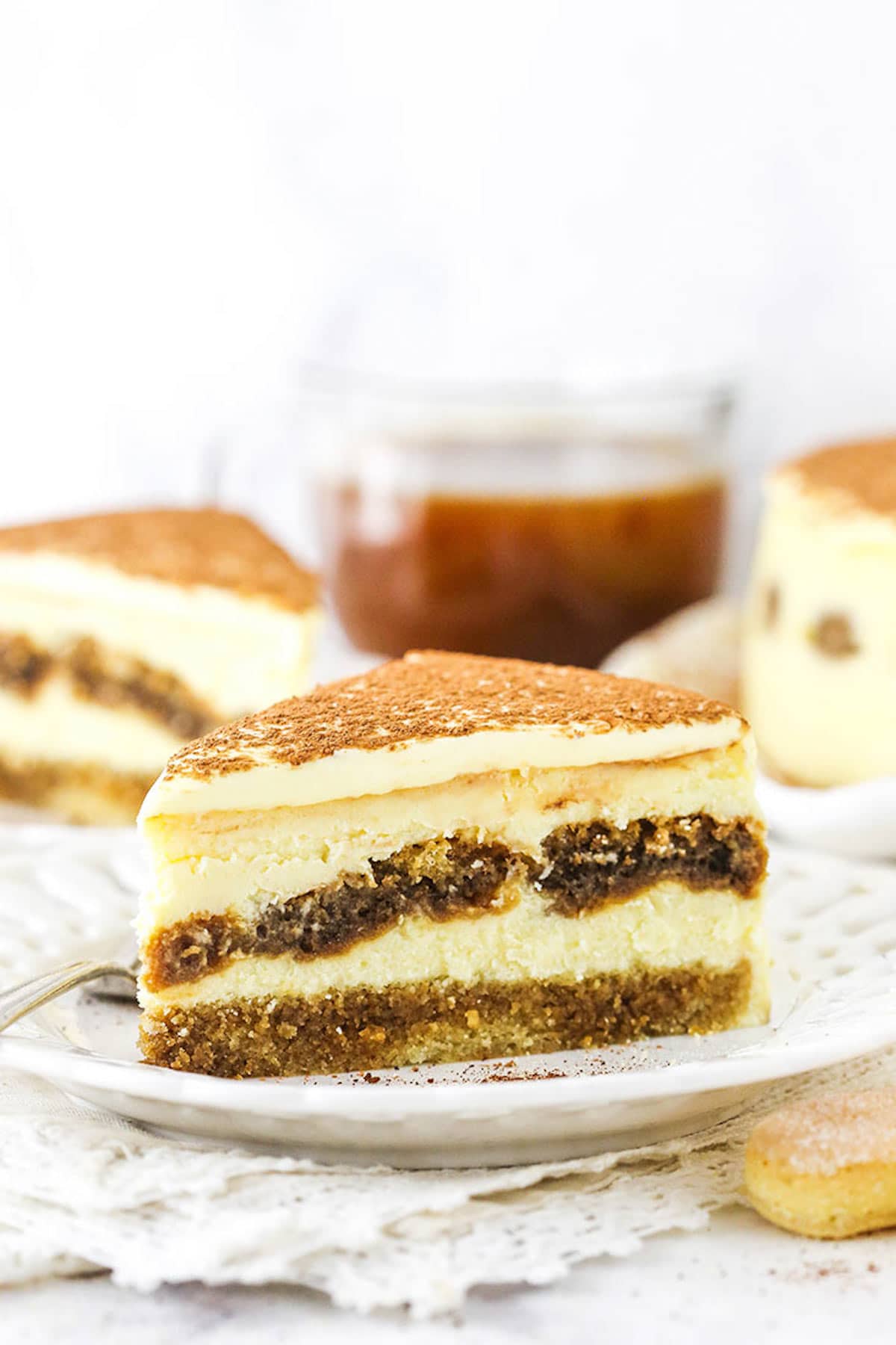 A Slice of Tiramisu Cake Sitting on a White Plate on Top of a Pile of Doileys