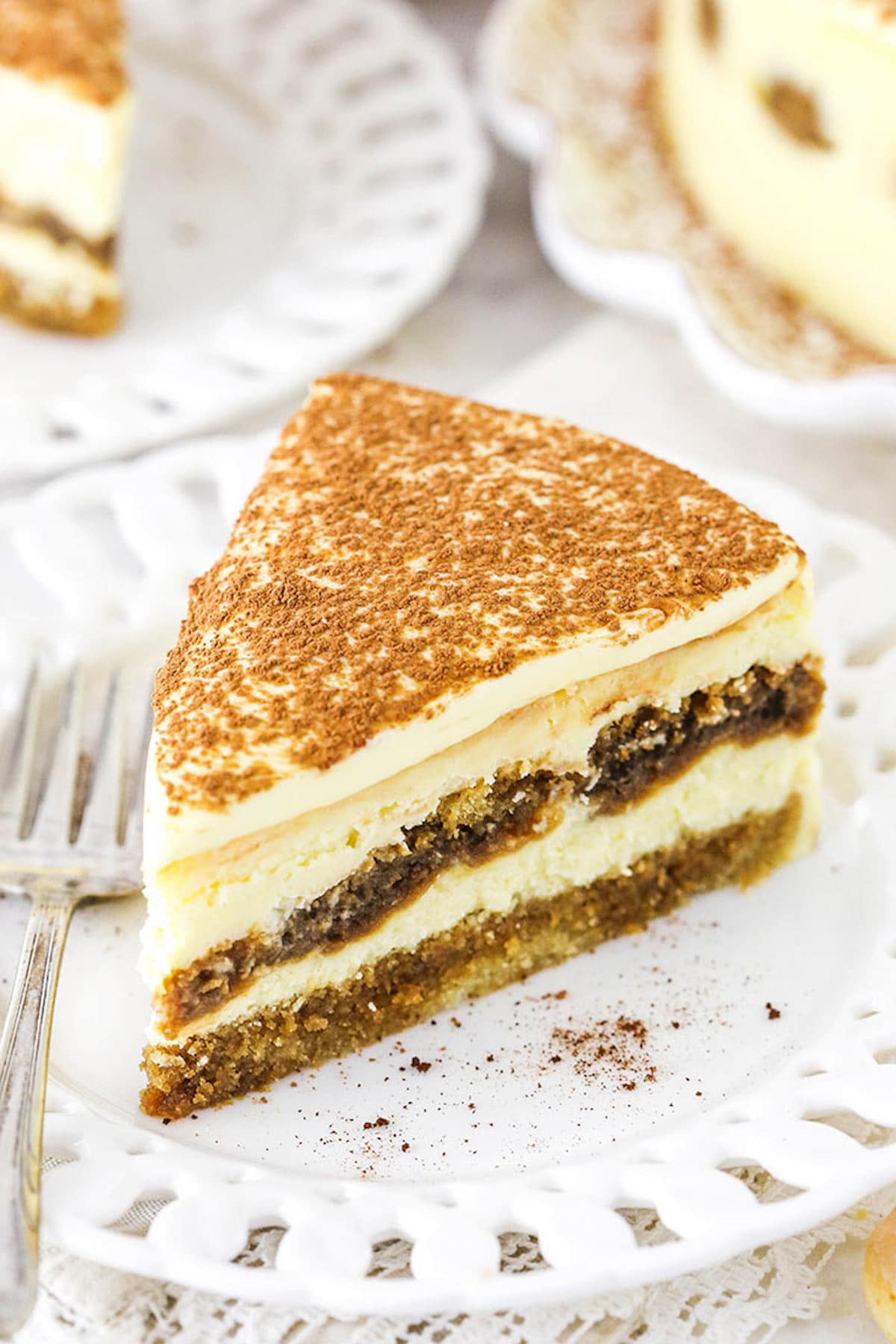 A Piece of the Ultimate Tiramisu Cheesecake on a White Plate with Decorative Edges