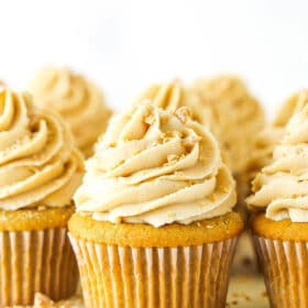 A homemade cupcake with buttercream frosting on a cake stand with more frosted cupcakes