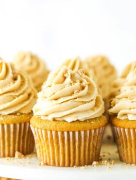 A homemade cupcake with buttercream frosting on a cake stand with more frosted cupcakes