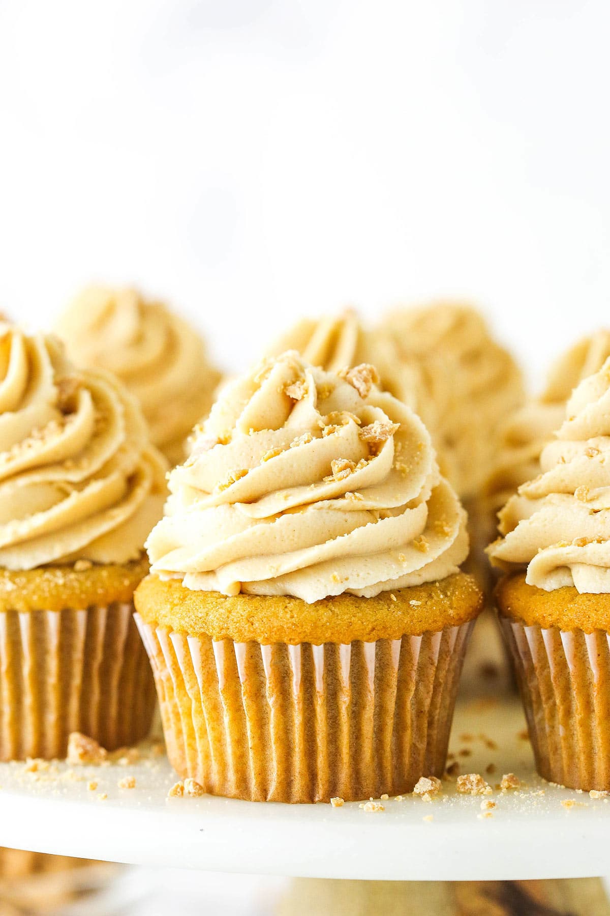 A homemade cupcake with buttercream frosting on a cake stand with more frosted cupcakes