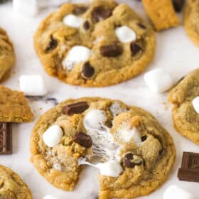 S'mores cookies on a marble countertop, one pulled in half to show the marshmallows