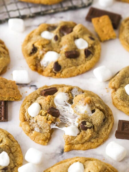 S'mores cookies on a marble countertop, one pulled in half to show the marshmallows
