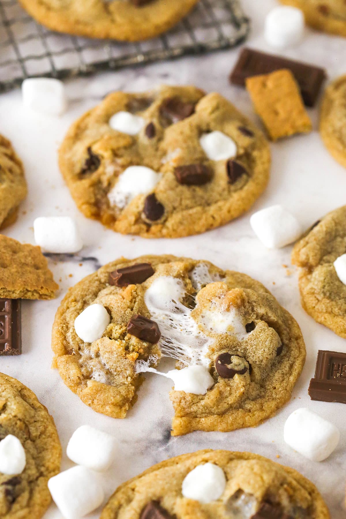S'mores cookies on a marble countertop, one pulled in half to show the marshmallows