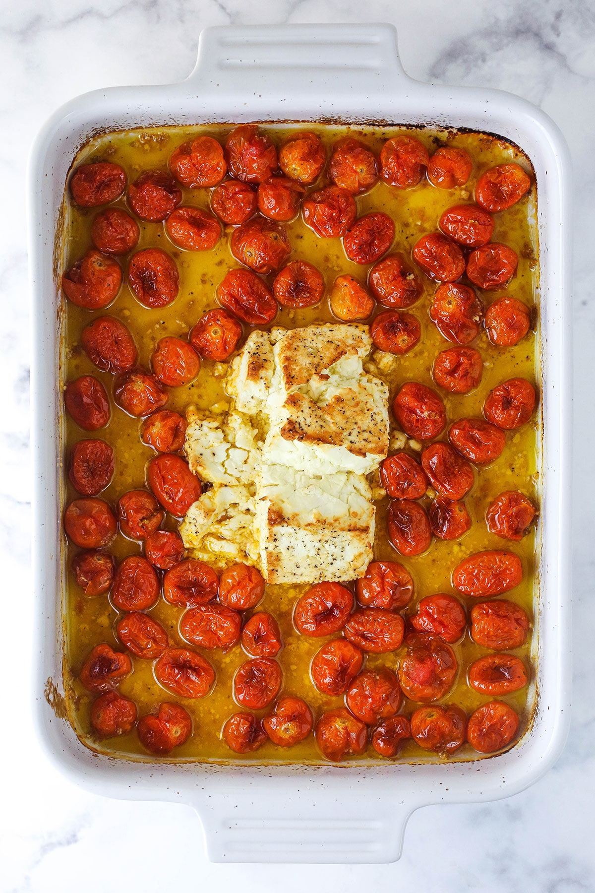 A baking dish filled with baked feta pasta before the garlic, basil and noodles have been added