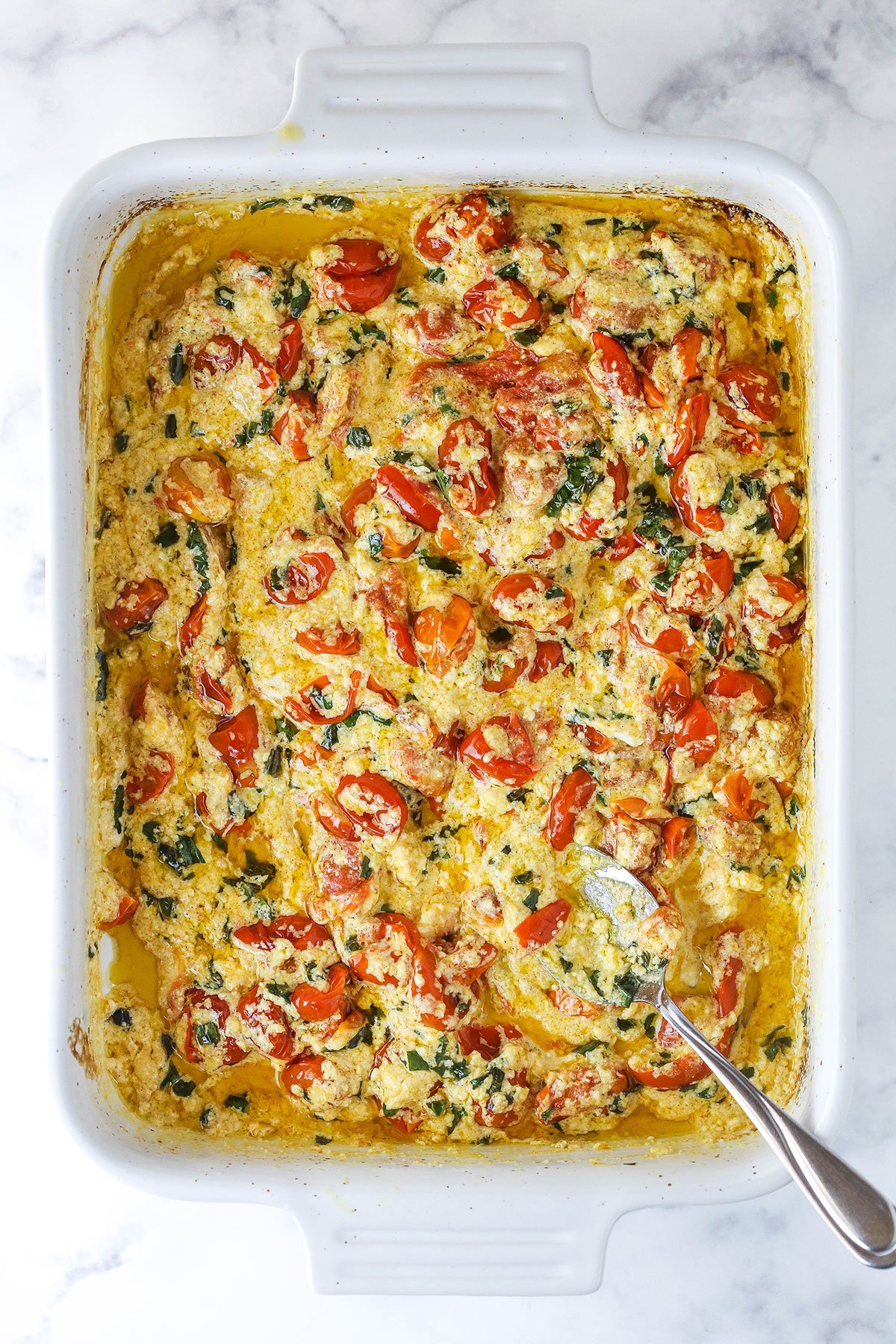 The baked tomato and basil mixture in a baking dish with the garlic and chopped basil mixed in