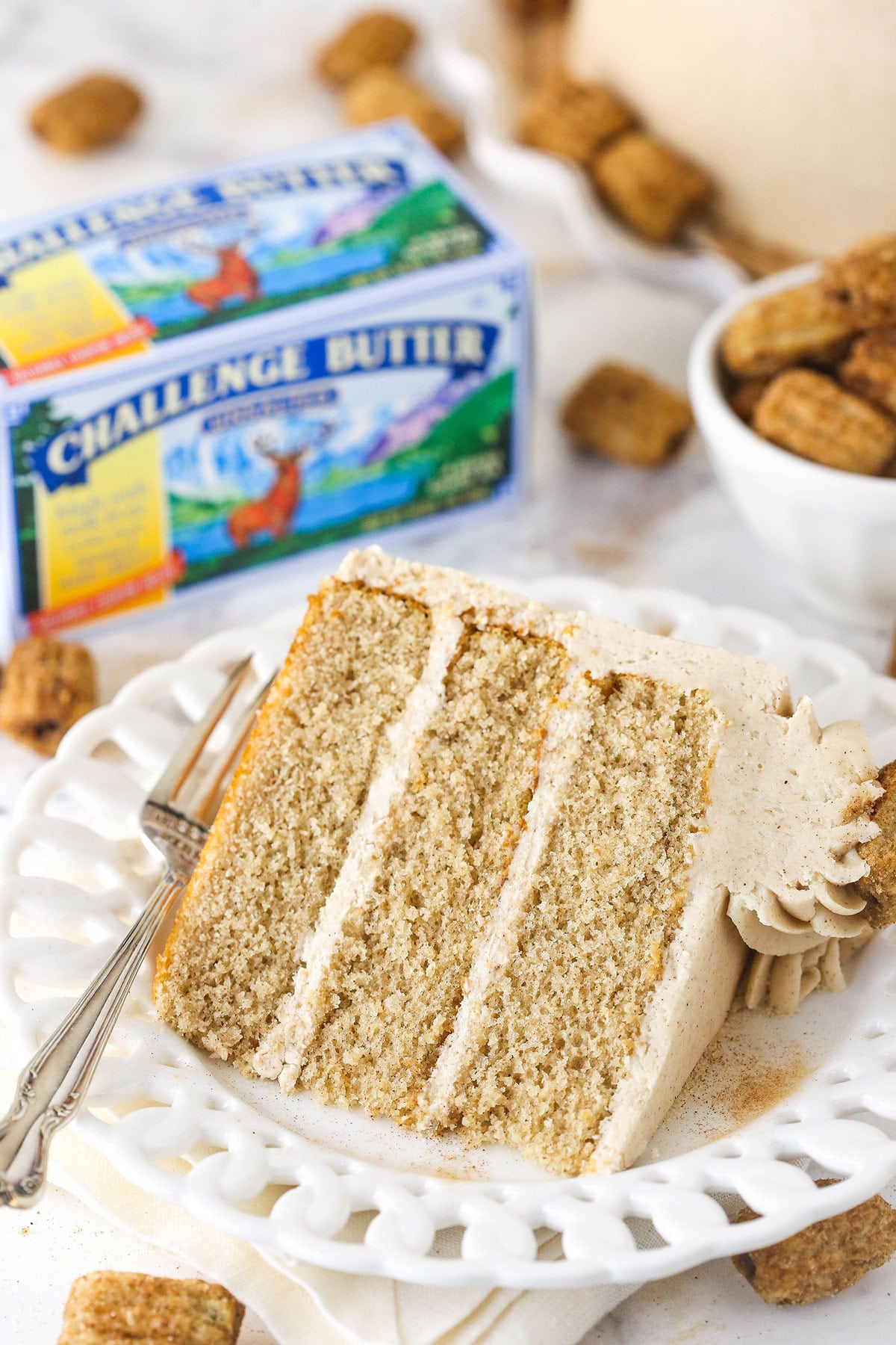 slice of churro cake on white plate with challenge butter in the background