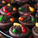 Chocolate cookies stuffed with buttercream frosting, covered with Oreo crumbs and topped with gummy worms