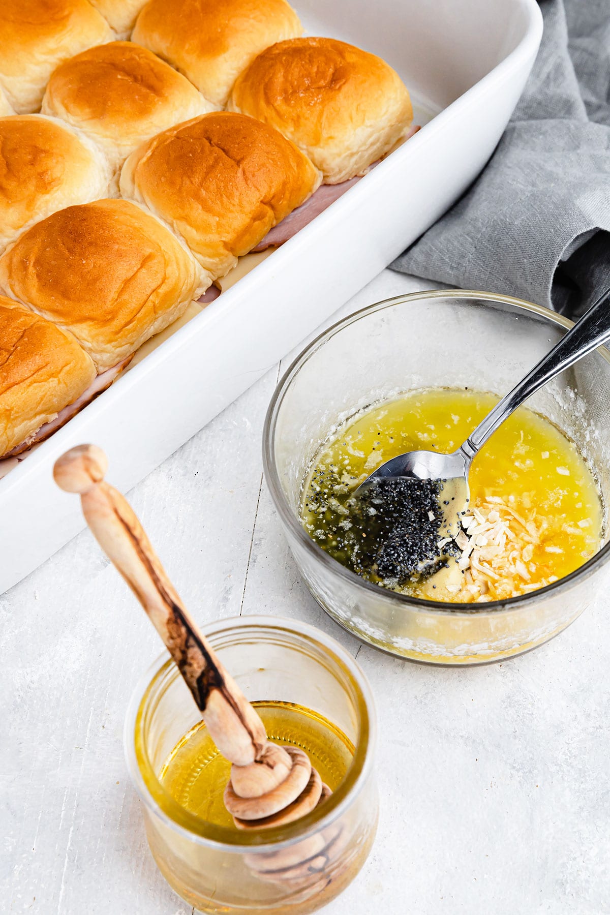 A bowl of honey beside a bowl containing the remaining glaze ingredients with the sliders in the background