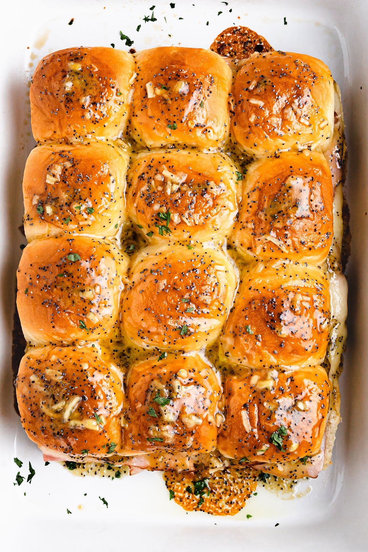 A bird's-eye view of a pan of twelve Hawaiian roll sliders