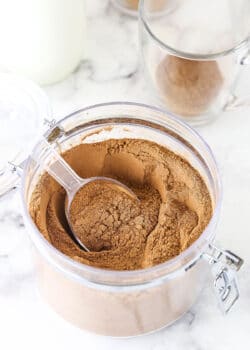 A jar filled with hot chocolate mix on top of a black and white marble counter