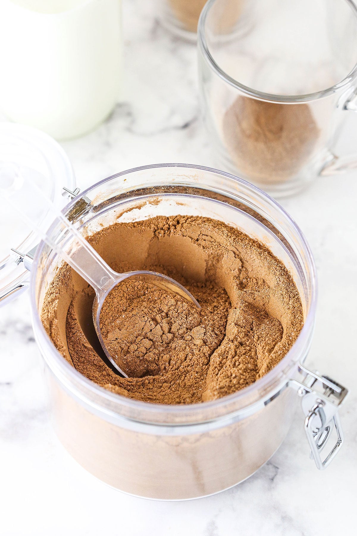 A jar filled with hot chocolate mix on top of a black and white marble counter