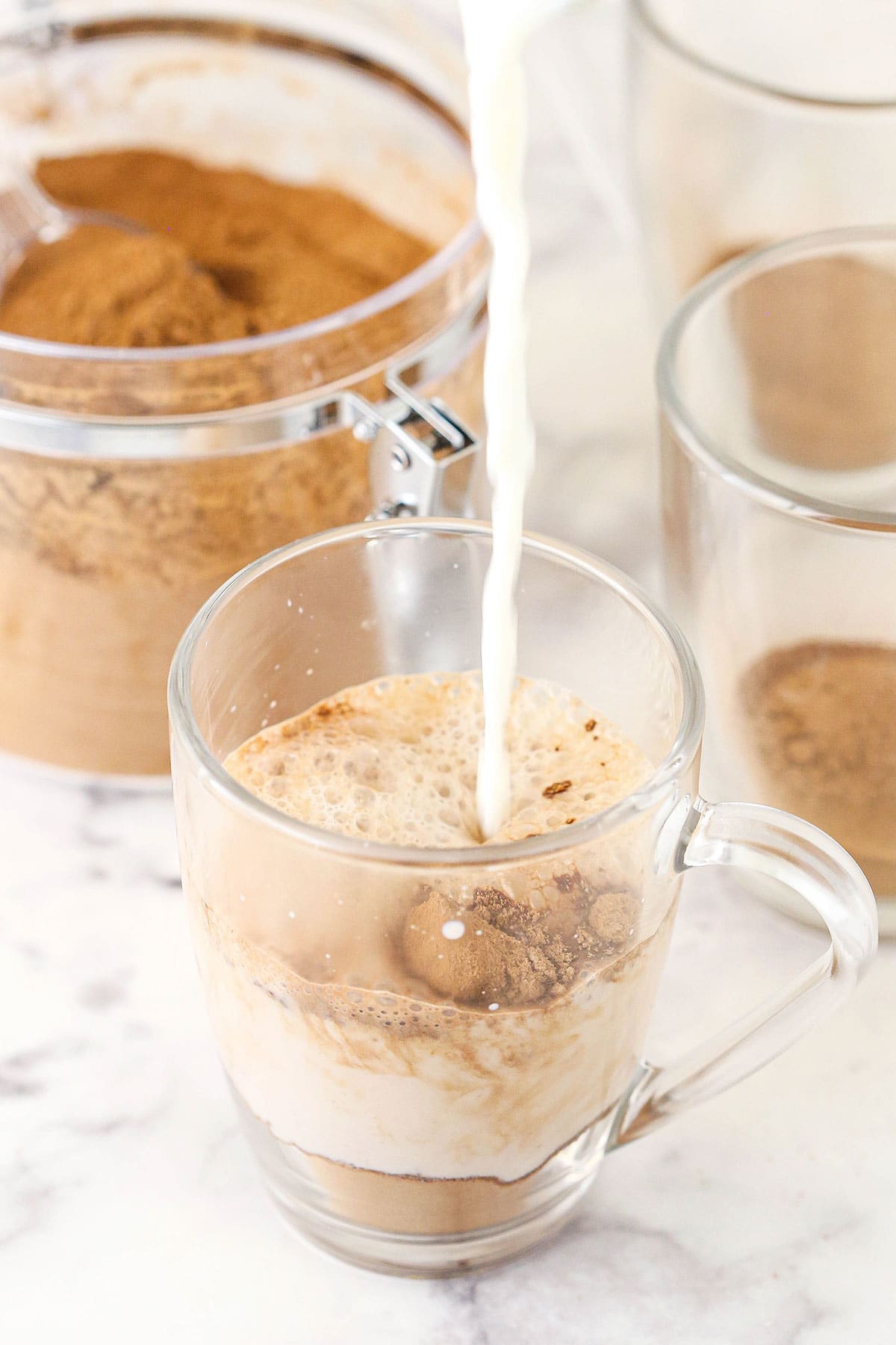 Hot milk being poured into a cup containing homemade hot cocoa mix