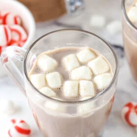 A serving of hot cocoa in a glass mug with melting mini marshmallows on top