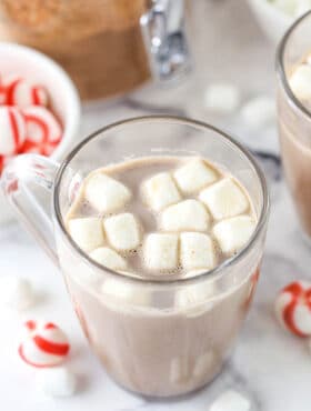 A serving of hot cocoa in a glass mug with melting mini marshmallows on top