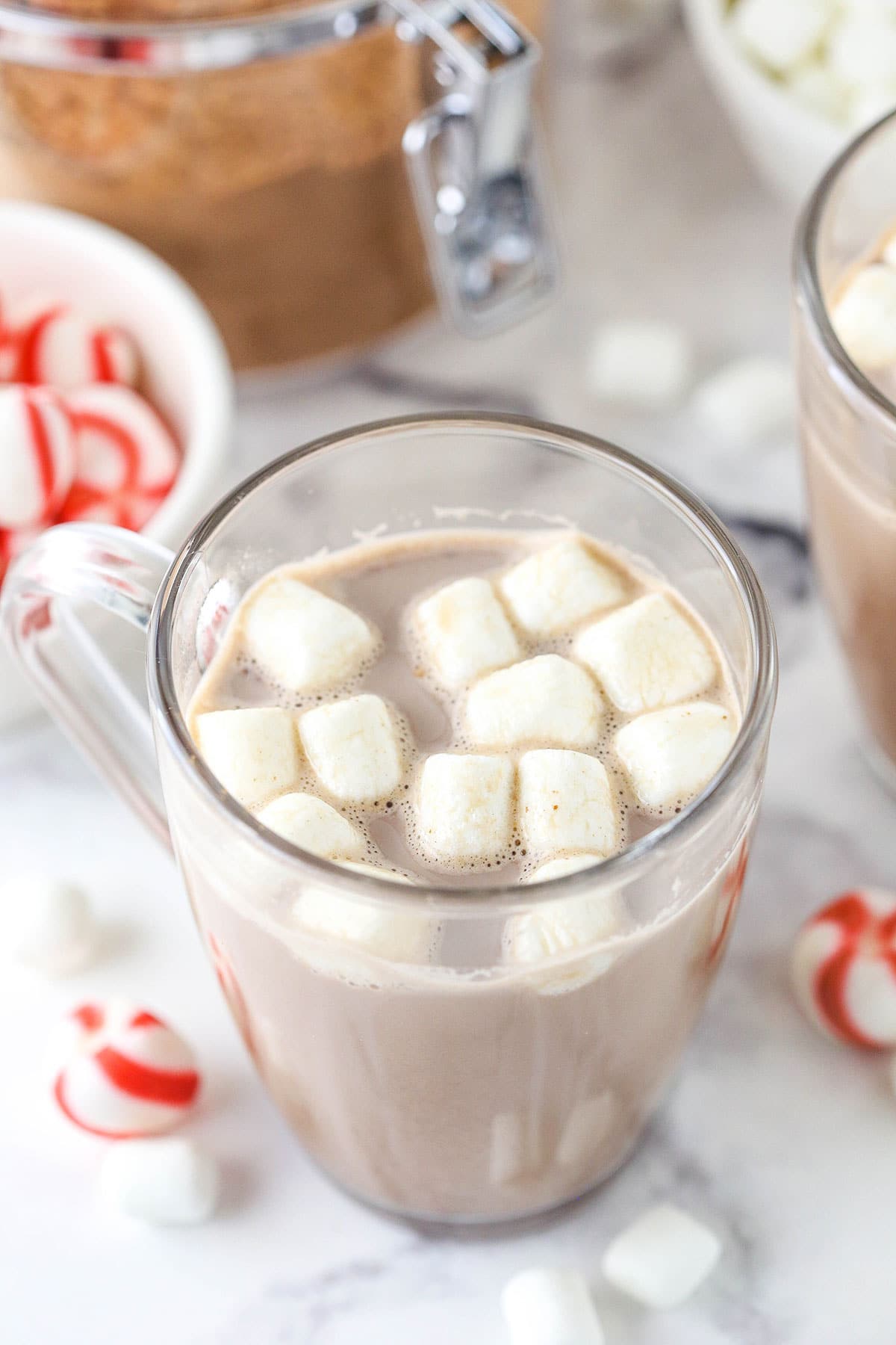 A serving of hot cocoa in a glass mug with melting mini marshmallows on top