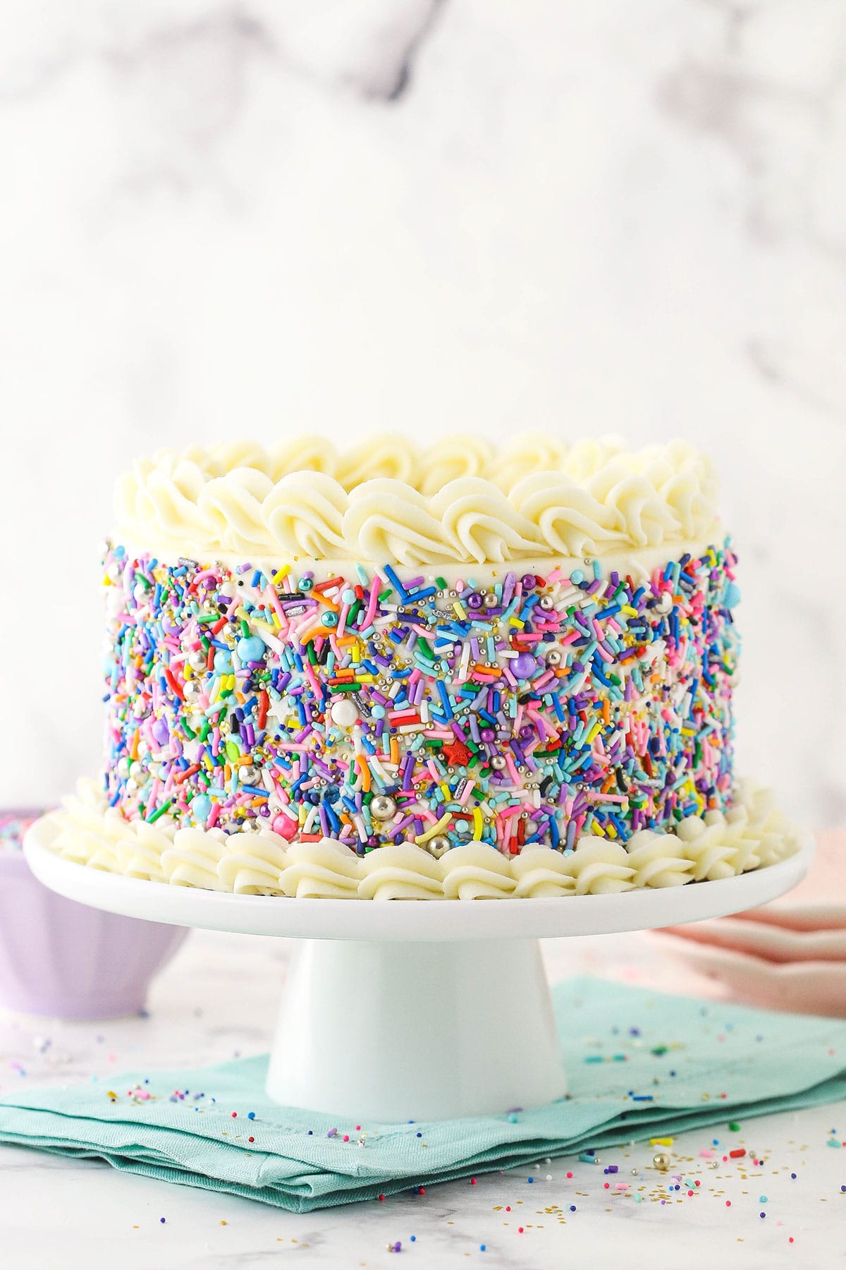 6 inch vanilla cake covered in sprinkles on blue napkin
