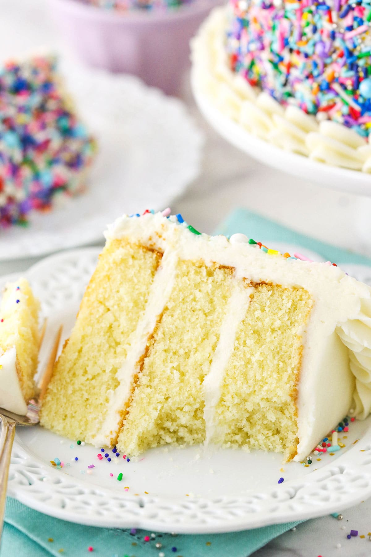 slice of vanilla cake with a bite taken on white plate