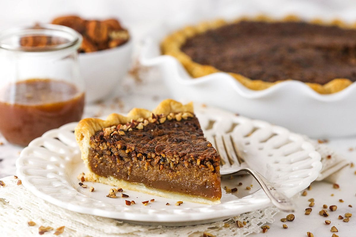 A piece of homemade pecan pie on a white plate with cutouts in the rim