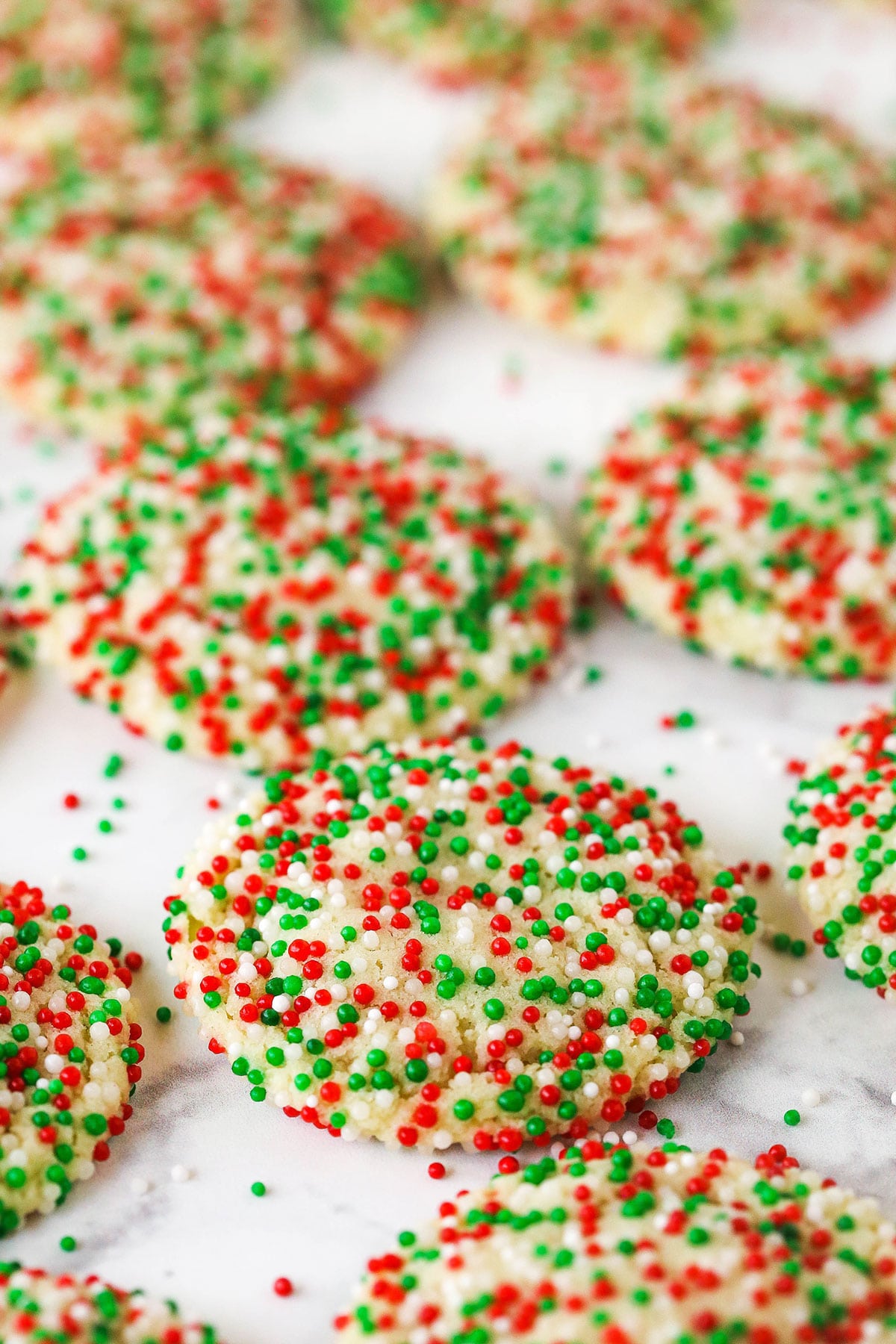 Christmas sprinkle cookies lined up on a marble countertop